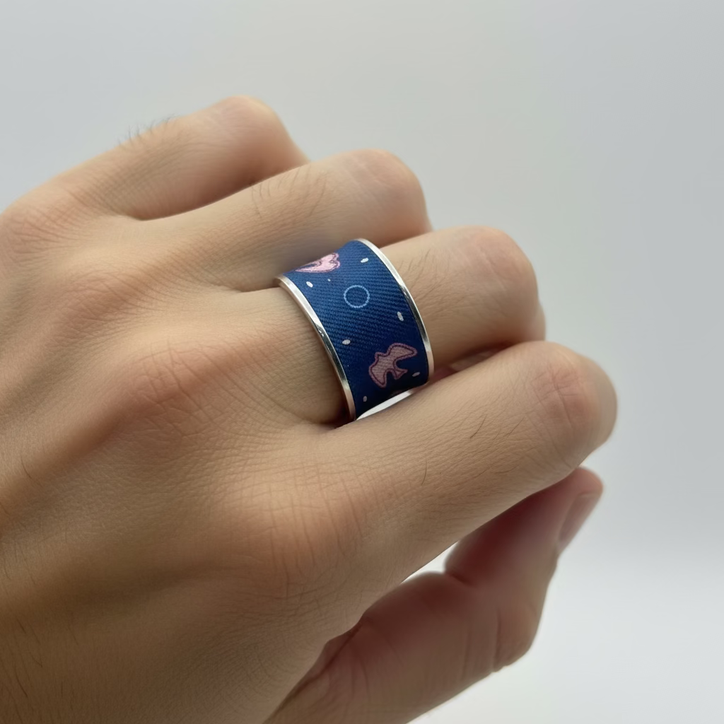 Bague en acier et soie bleue marine et rose . motif hirondelles. portée par un homme.